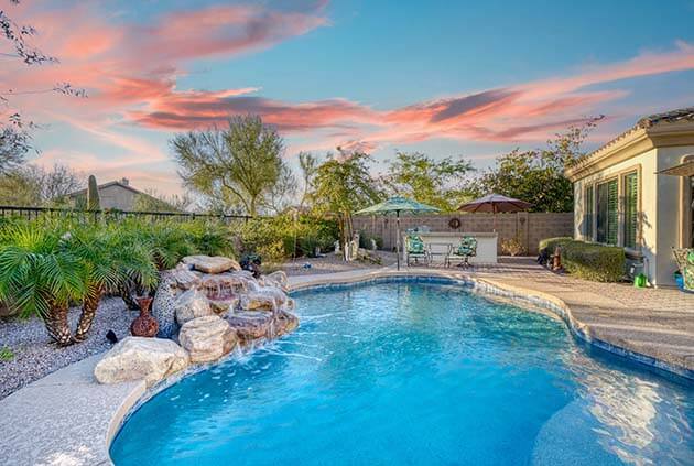 Luxury home pool at sunset with a waterfall